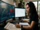 A focused woman at a two-monitor desk with an actual rug pull chart crash and a checklist of warning signs she is checking off, for a crypto trading article.
